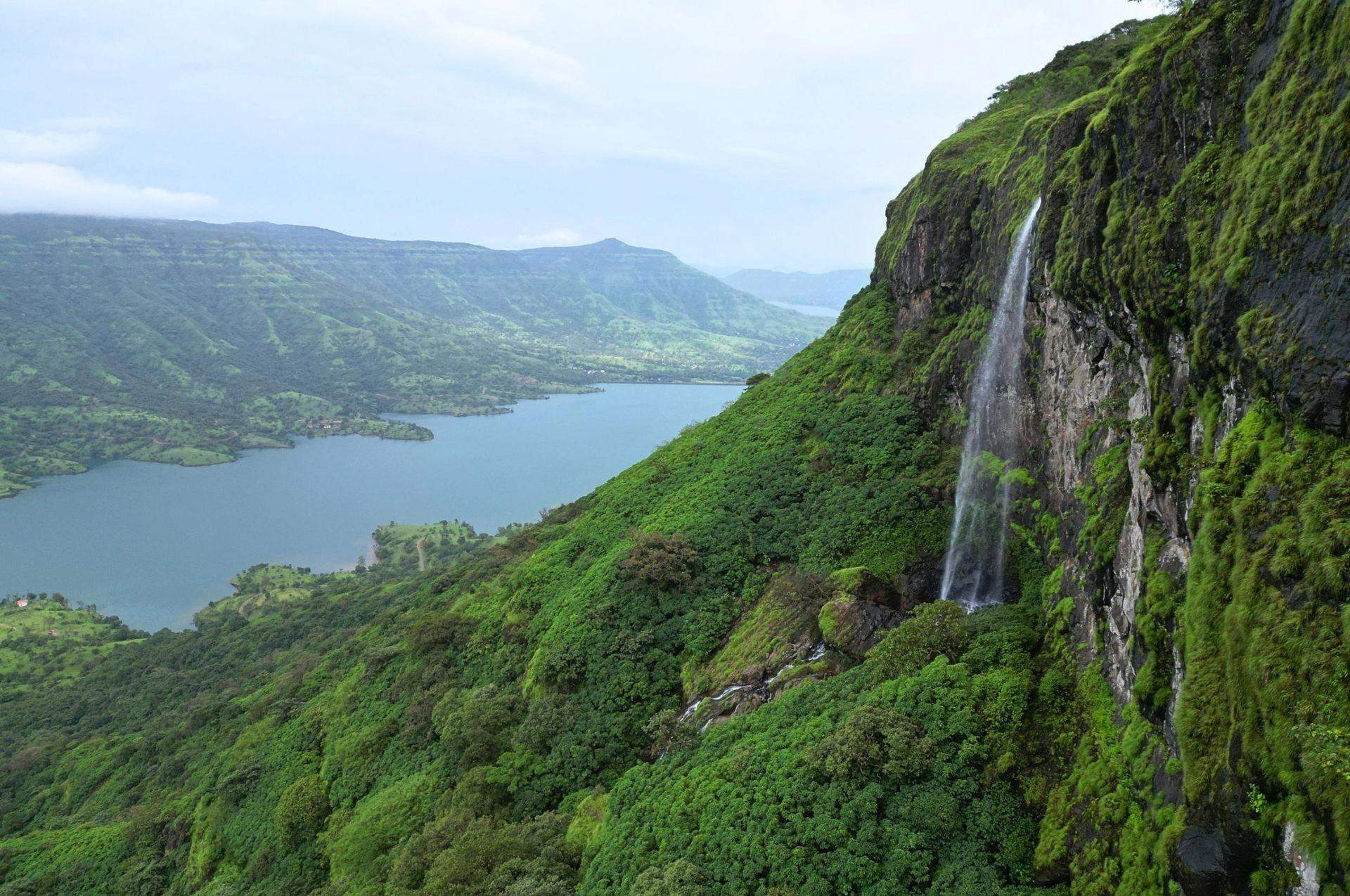 Scenic view of a lush green valley with a waterfall cascading from the cliffside.